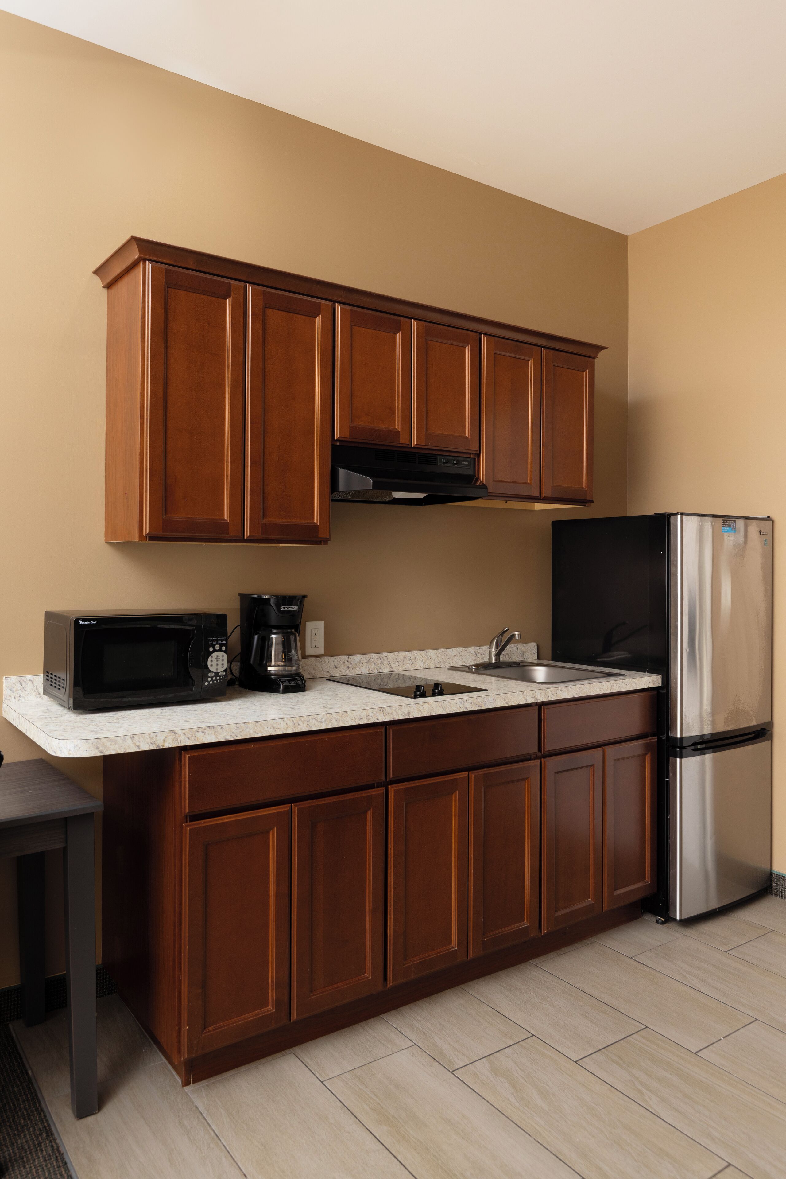 A kitchen with wooden cabinets, a stainless steel refrigerator, a microwave, and a coffee maker.
