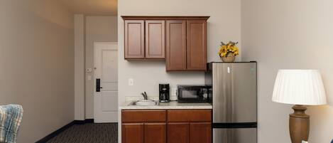 A compact hotel room with a kitchenette, including a refrigerator, microwave, and coffee maker.