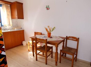 Eine kleine Küche mit Holzausstattung, einem Esstisch mit Stühlen und einem kleinen Topfpflanzen.
