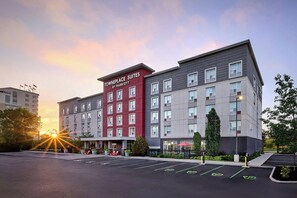 Ein mehrstöckiges Hotel mit einer markanten roten und grauen Fassade, beschriftet mit 'TOWNEPLACE SUITES BY MARRIOTT'.