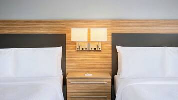 Ett hotellrum med två sängar, en sänggavel i trä, ett nattduksbord med en lampa och en byrå.