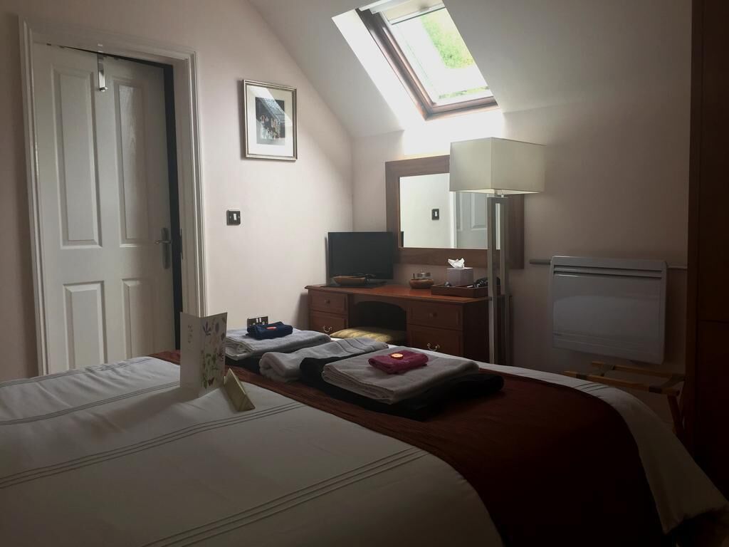 Une chambre d’hôtel équipée d’un lit, d’un bureau, d’une chaise, d’une lampe, d’un téléviseur et d’une lucarne.