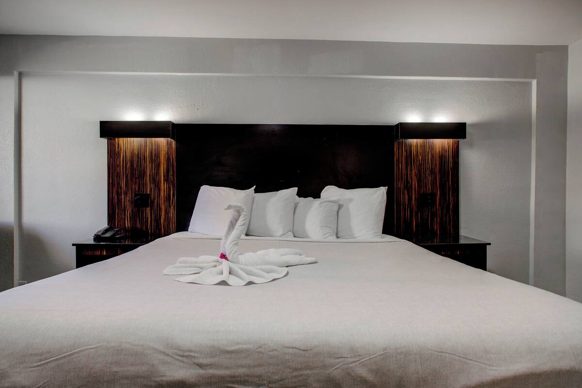 Un lit bien fait, avec du linge de lit blanc et une serviette décorative joliment disposée.