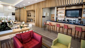 A modern hotel lobby with a reception desk, seating area, bar, and a television screen. - Hilton Garden Inn Erzincan (Erzincan)