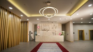 A modern reception area with a reception desk, a red carpet, and a unique circular light fixture. - Hilton Garden Inn Erzincan (Erzincan)