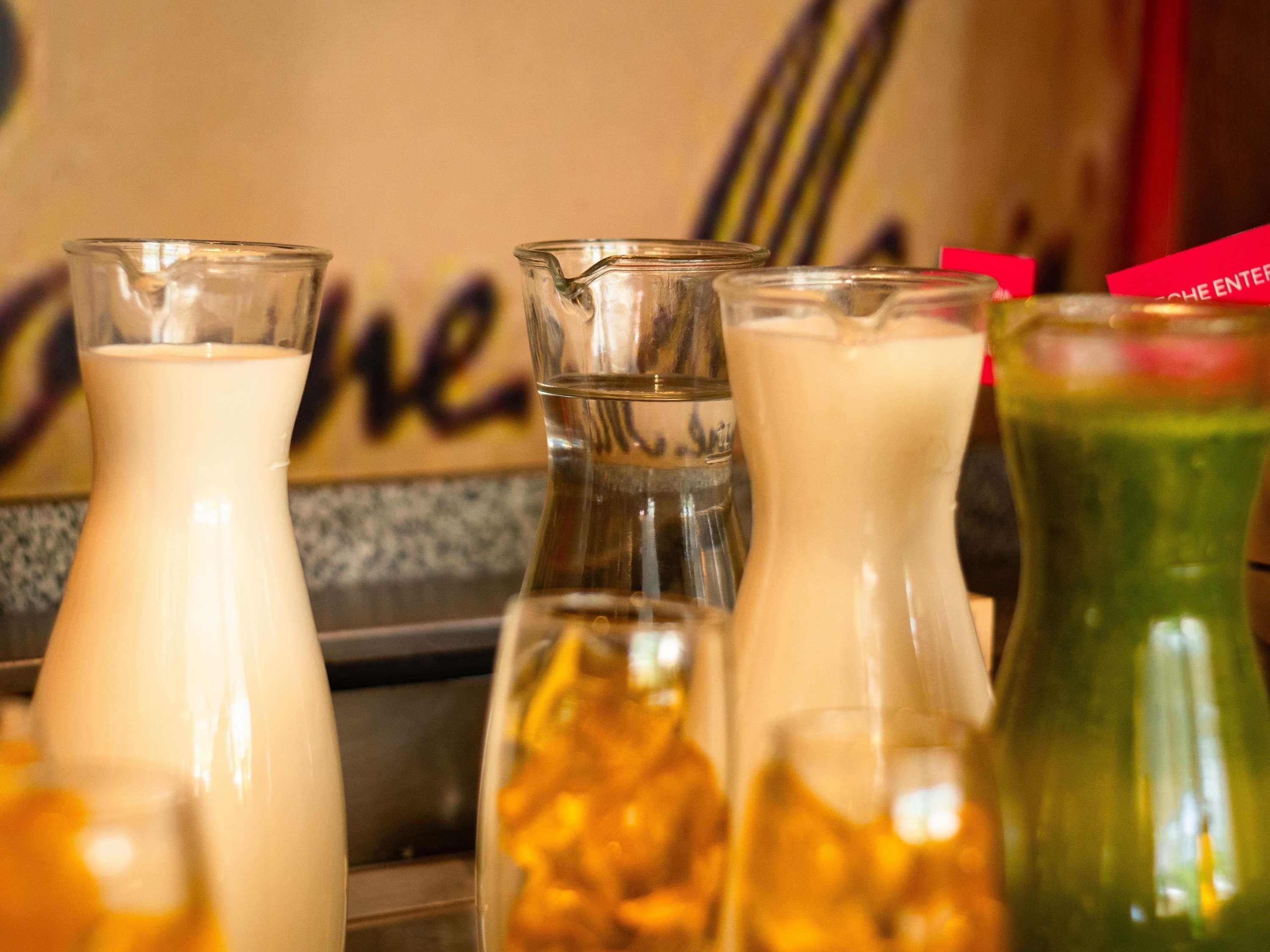 A variety of beverage dispensers, including a milk jug and a green bottle with a straw.
