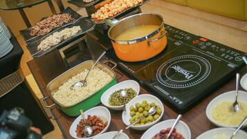 A buffet with various dishes and a large pot on an induction cooktop.