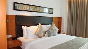 Una habitación de hotel con cama, mesita de noche, una obra de arte en la pared y ventana con cortinas.