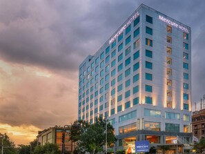 Een hoog, modern hotelgebouw met een bord waarop 'Mercure Hotel' staat.