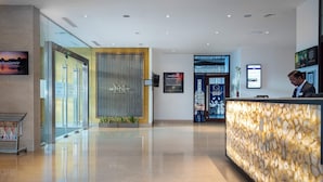 Et hotellets receptionområde med moderne design, inklusive en receptionsdisk, en stor skærm og en glaskledå.
