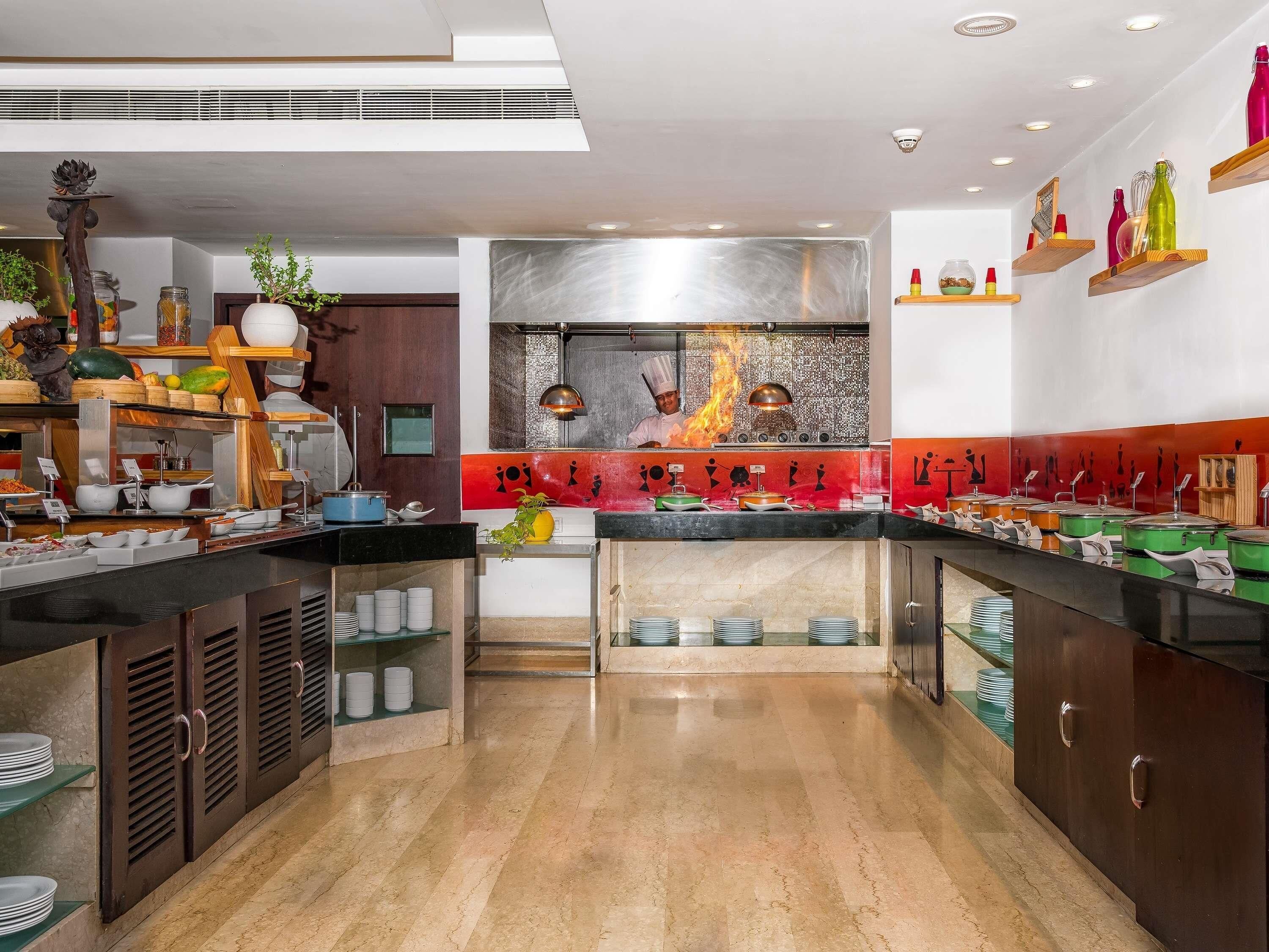 A modern kitchen with a central island, a stainless steel backsplash, and a variety of food containers and utensils.