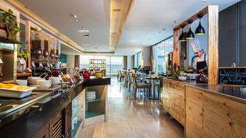 A modern restaurant with a buffet area, wooden accents, and a view of the sea.