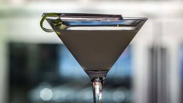 A martini glass with a lime twist on a bar counter.