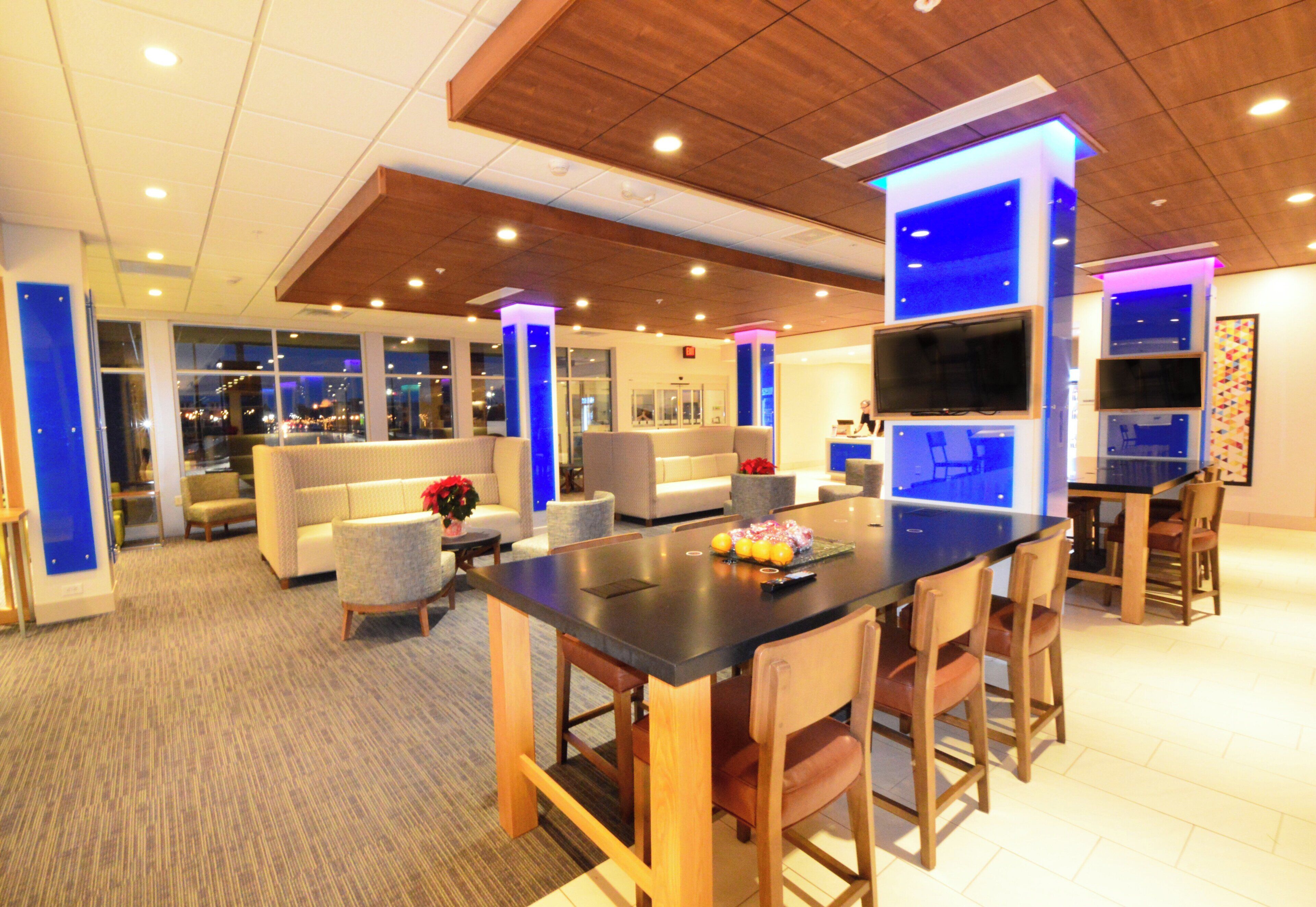 Een moderne hotel lobby met een bar, zitplaatsen en een groot raam met uitzicht op de stad.