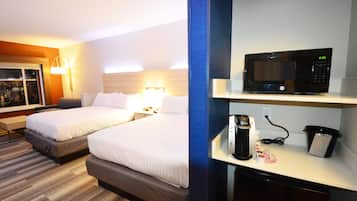A hotel room with two beds, a microwave, a coffee maker, and a trash bin.