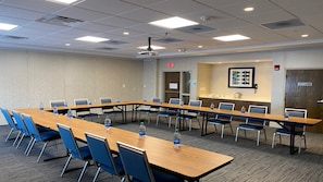 A conference room with a long table, chairs, water bottles, a projector, and a coat closet. - Holiday Inn Express & Suites Toledo South - Perrysburg by IHG (Perrysburg)