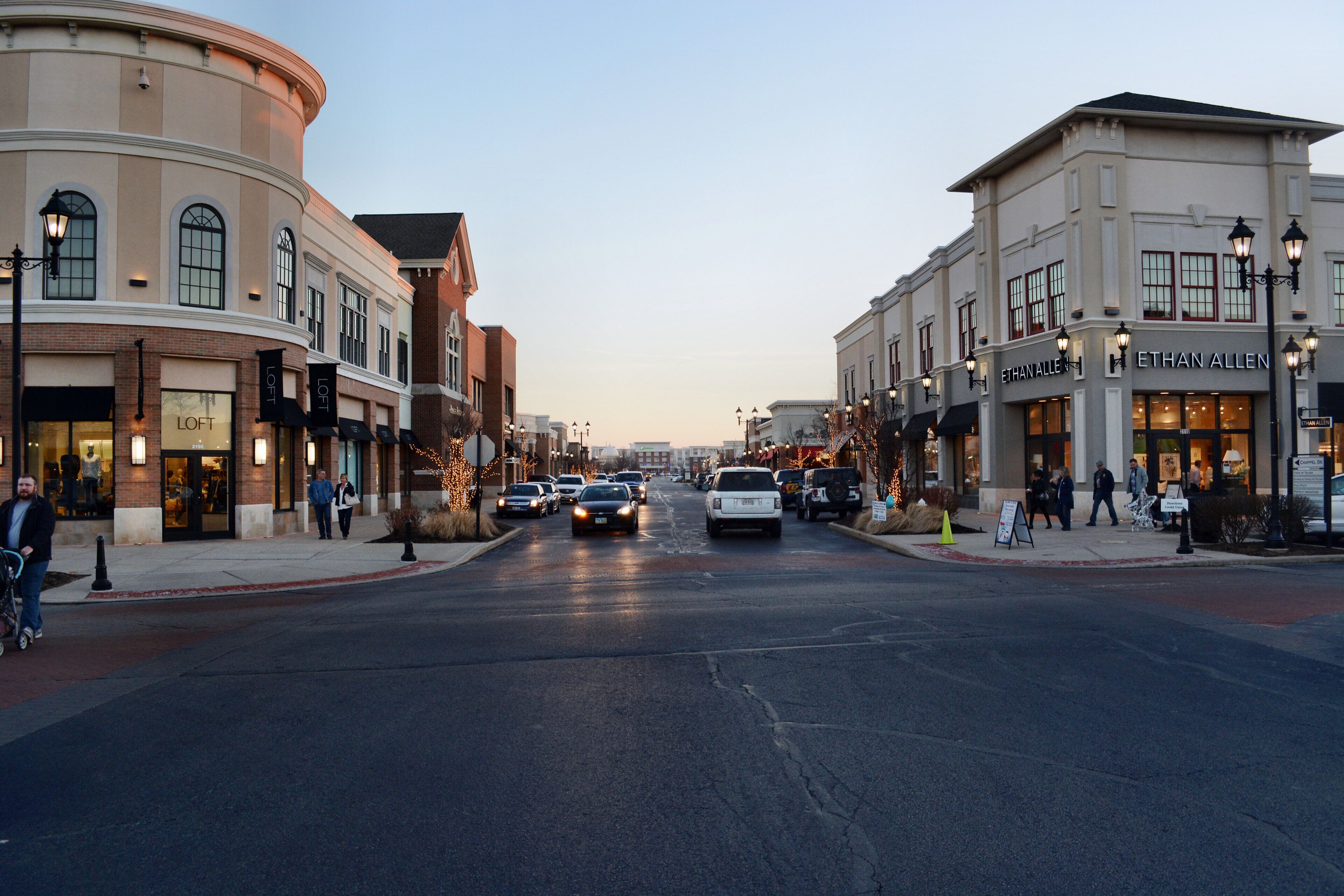 A street lined with shops and a building with a circular feature on the left.