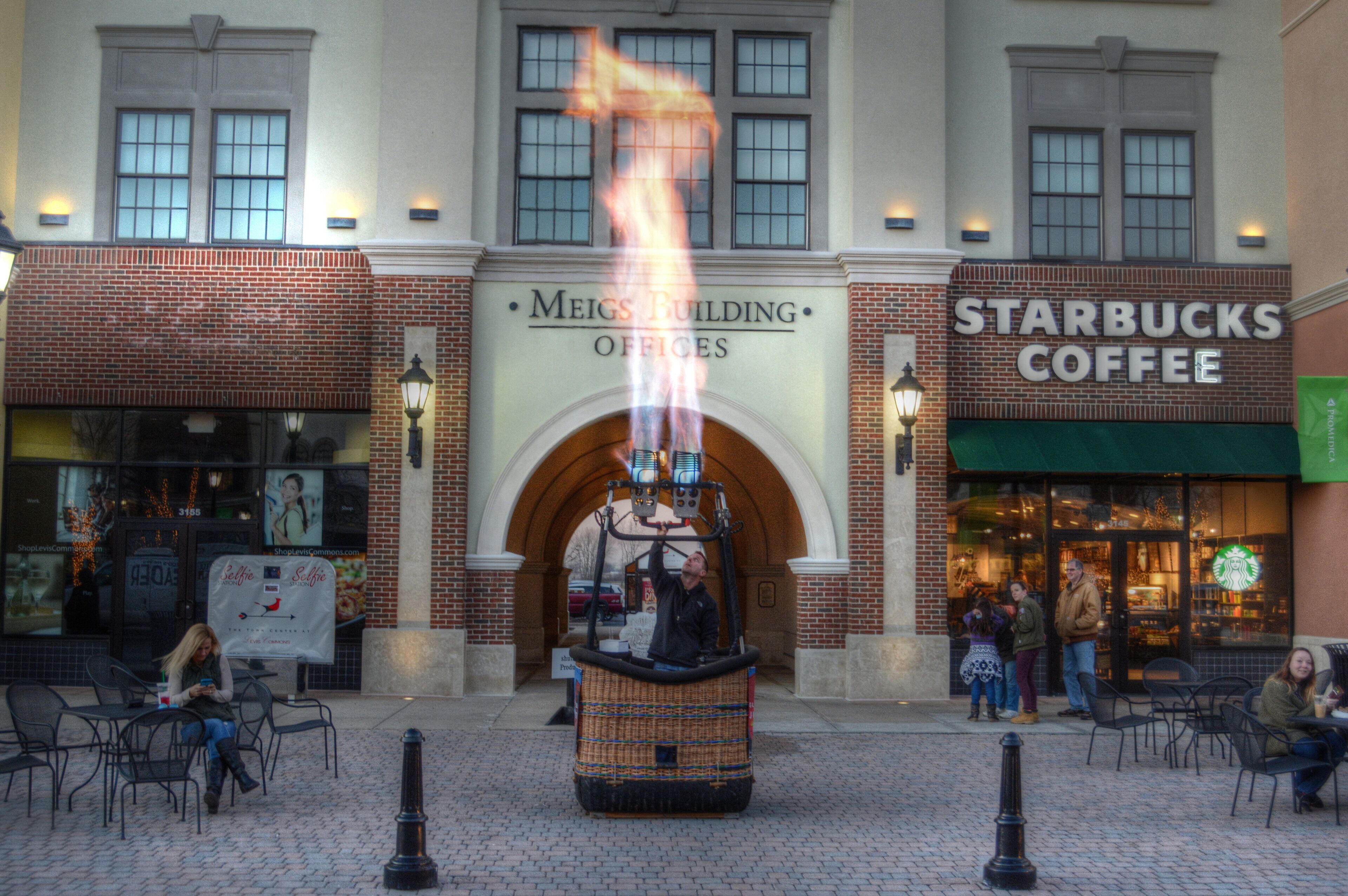 A building with a brick facade, a Starbucks Coffee sign, and a fire display in the center.