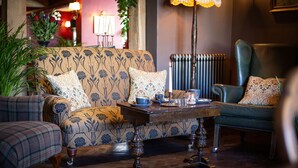 A cozy living room with a floral-patterned sofa, a green armchair, and a wooden coffee table with decorative items.
