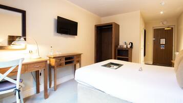 Une chambre d’hôtel équipée d’un lit, d’un bureau, d’une chaise, d’une télévision et d’une armoire.