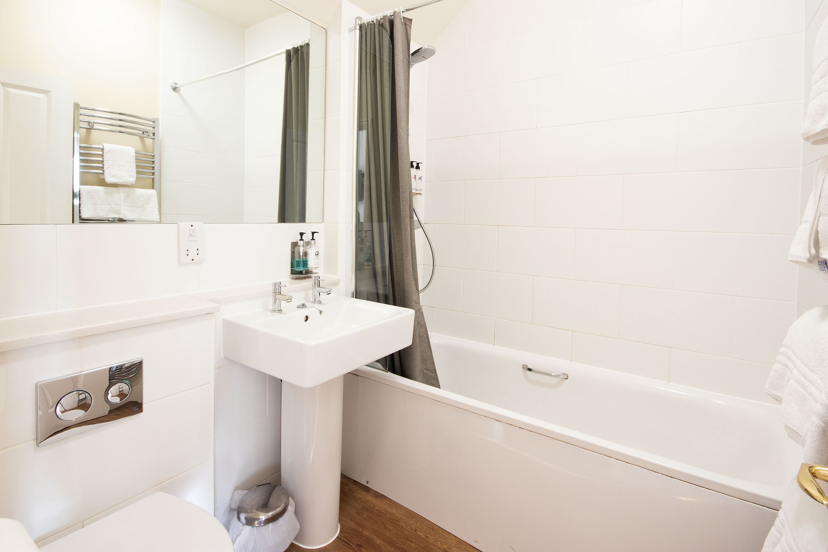 A modern bathroom with a white sink, mirror, and bathtub.