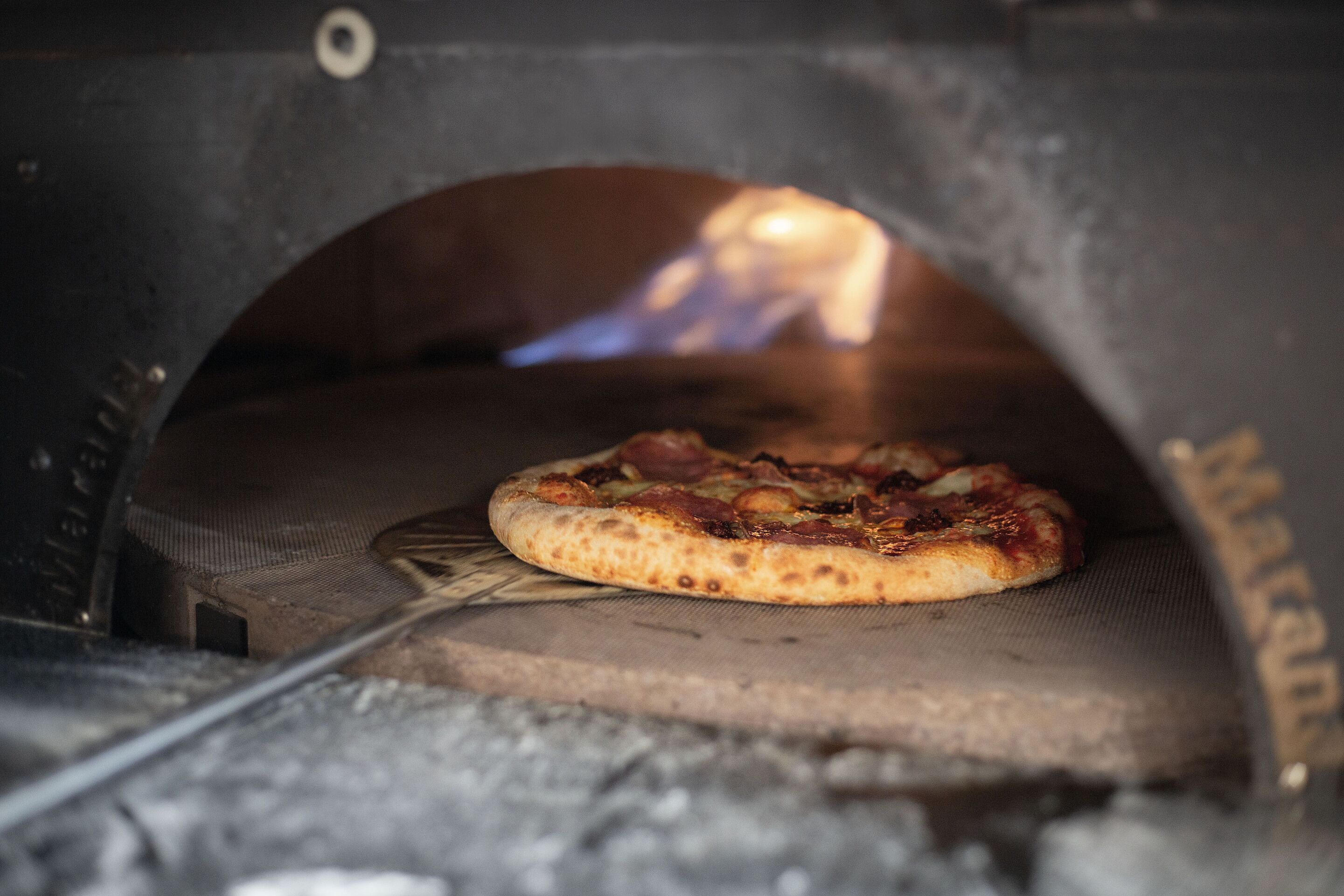 A pizza inside a wood-fired oven.