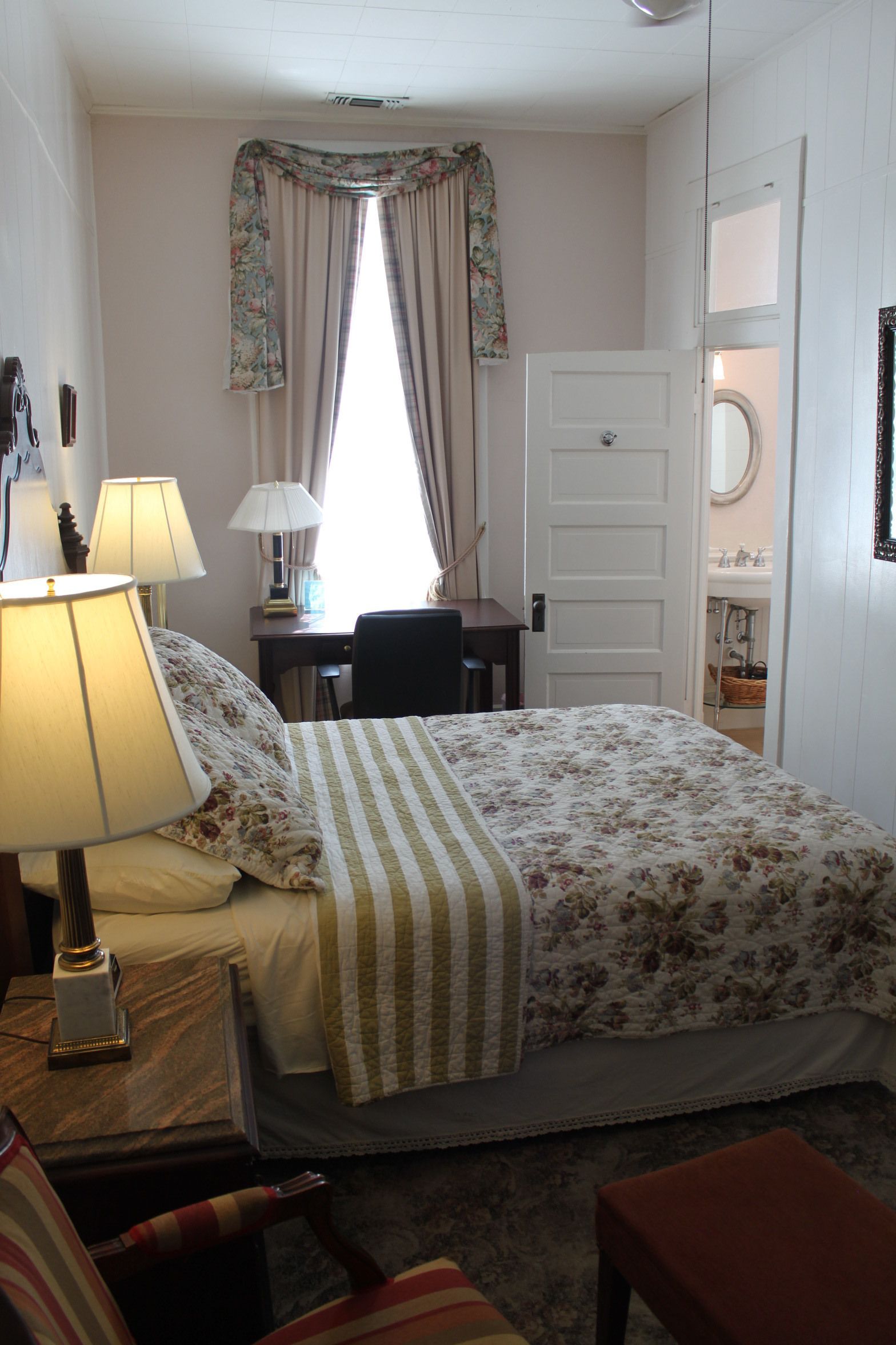 Une chambre à coucher avec un lit, deux lampes de chevet, un bureau et une chaise.