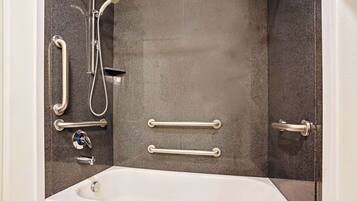 Un baño moderno con bañera, barras de apoyo, cabezal de ducha y grifo.