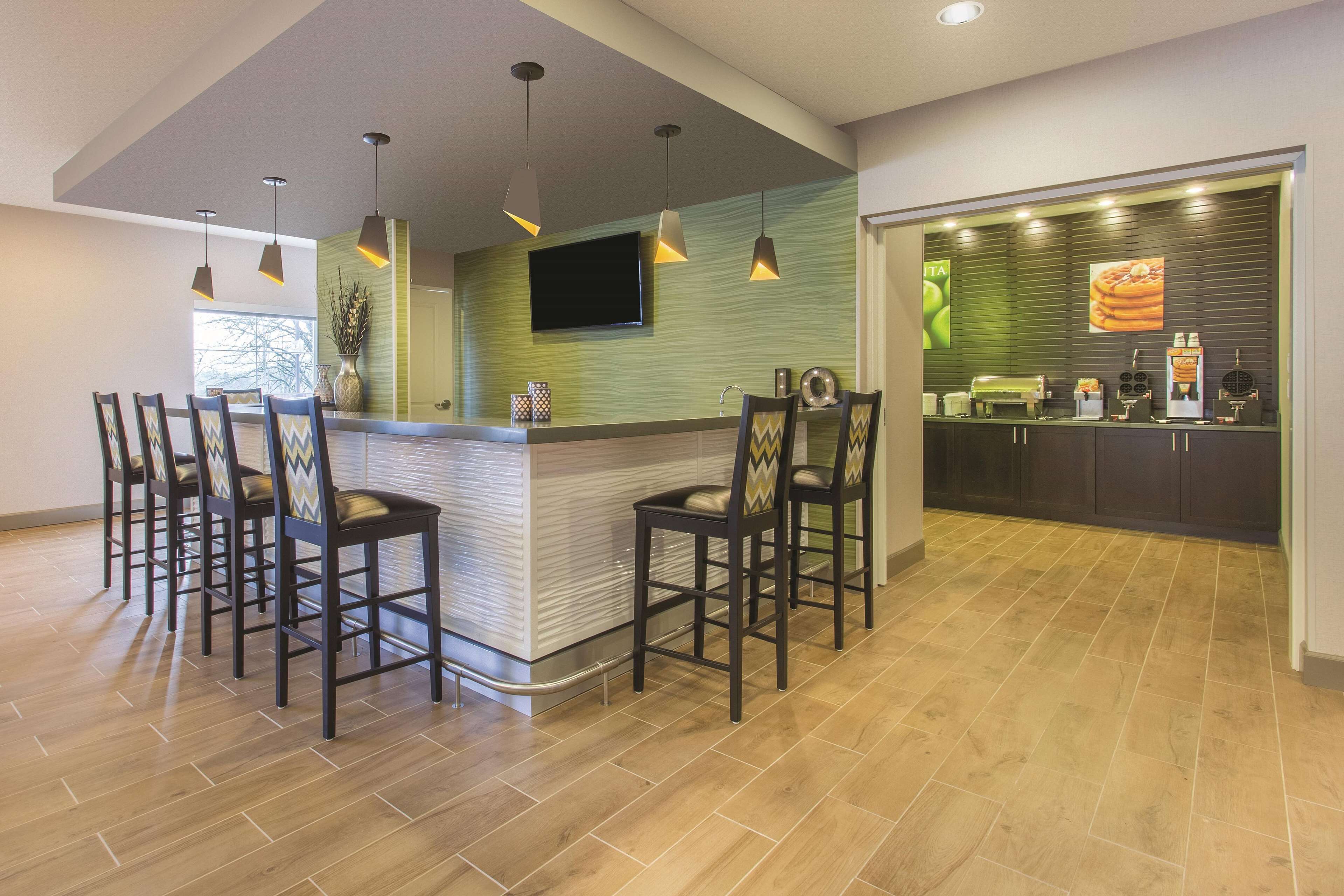 Una cocina moderna con barra, piso de madera e iluminación colgante.