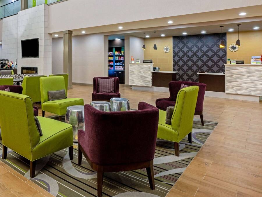 A lobby with green and maroon chairs, a reception desk, and a television mounted on the wall.