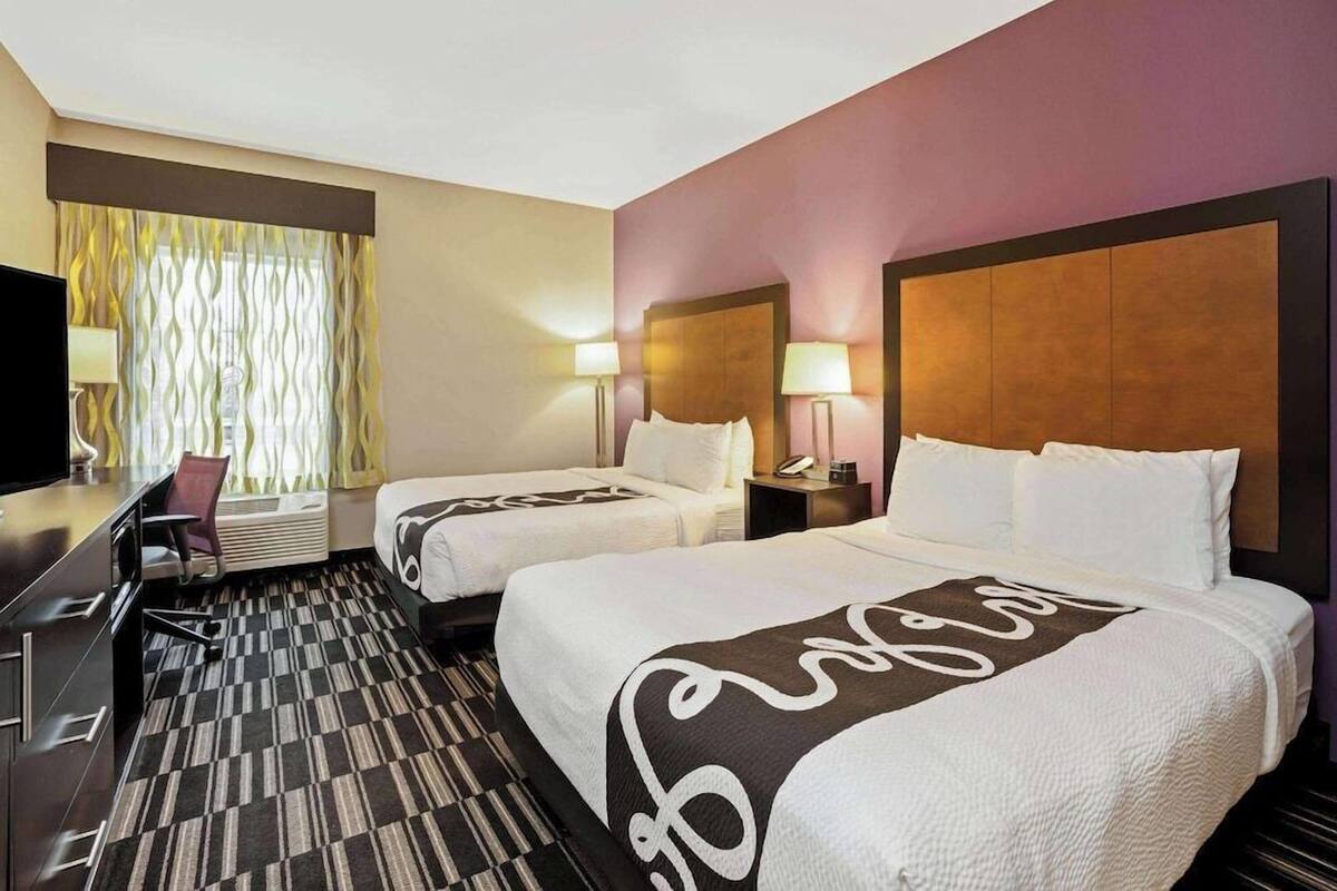 Habitación de hotel con dos camas, un escritorio y una silla.