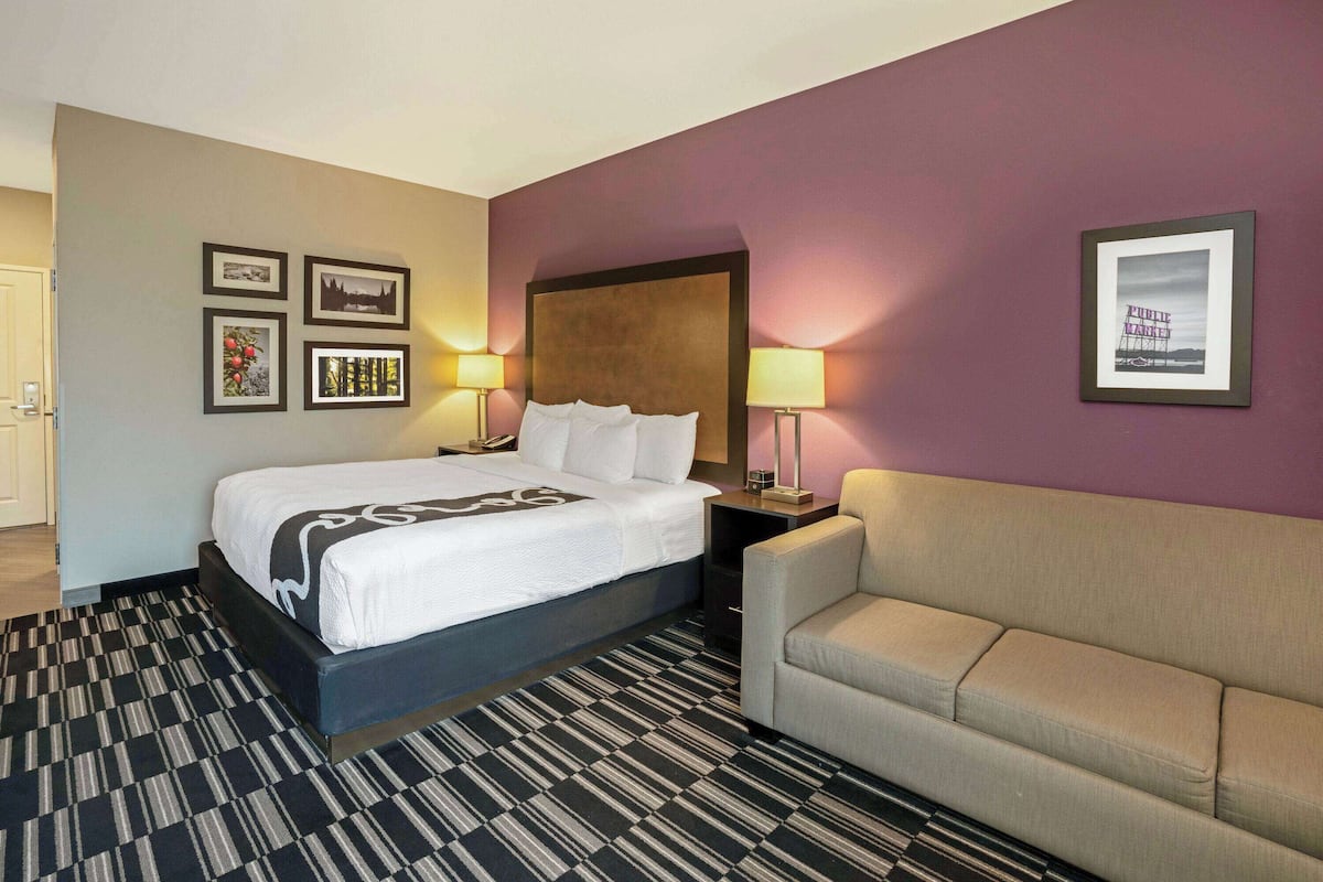 Una habitación de hotel con una cama, un sofá, un cabecero y cuadros enmarcados en la pared.