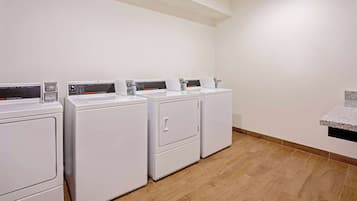 A laundry area with four white washing machines and a granite countertop.