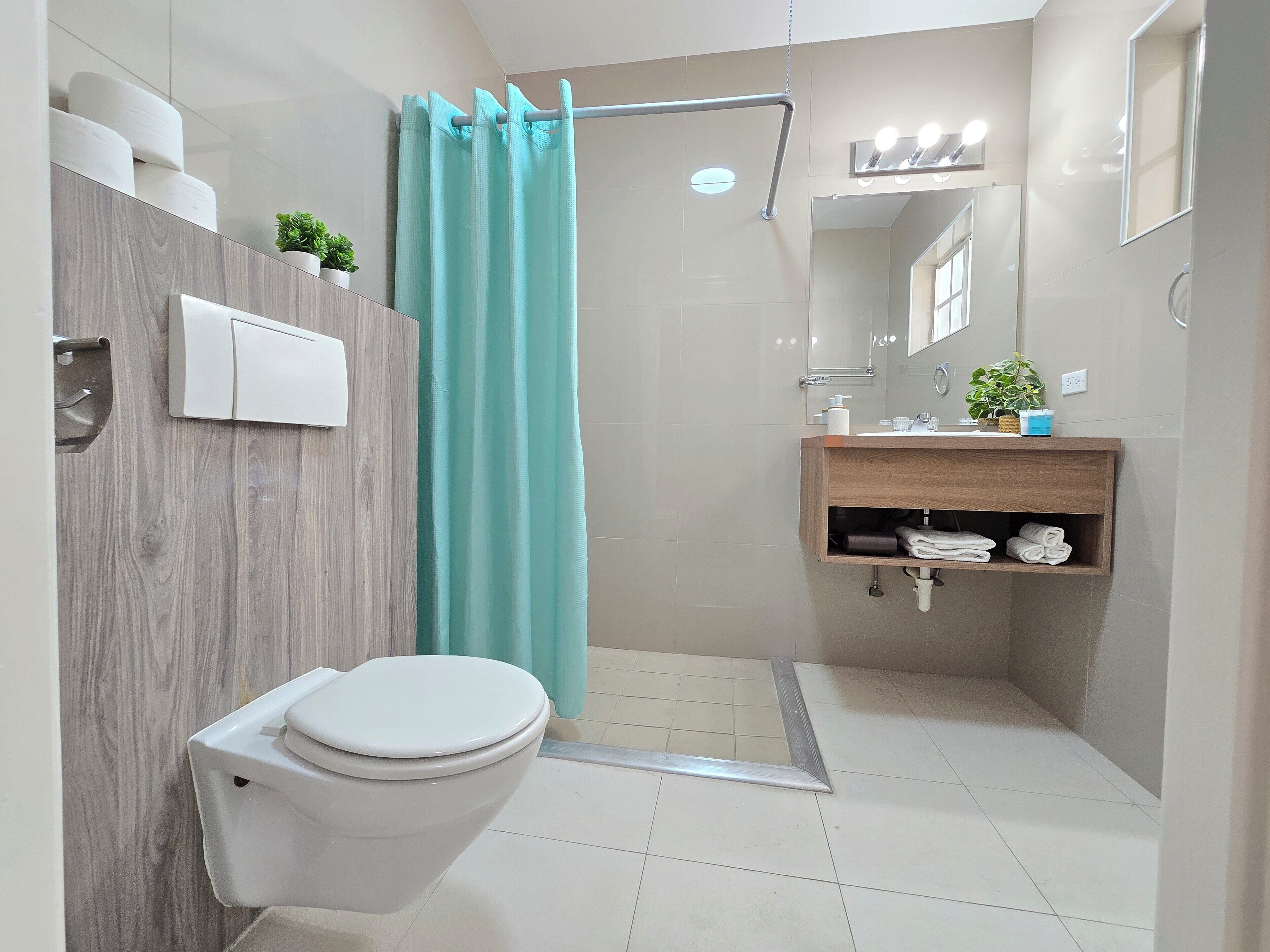 Un baño moderno con inodoro, ducha y zona de lavamanos.