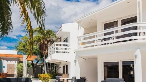 A modern poolside area with a clear blue pool, outdoor seating, and a two-story building with balconies. - Bubali Villa & Apartments (Oranjestad)