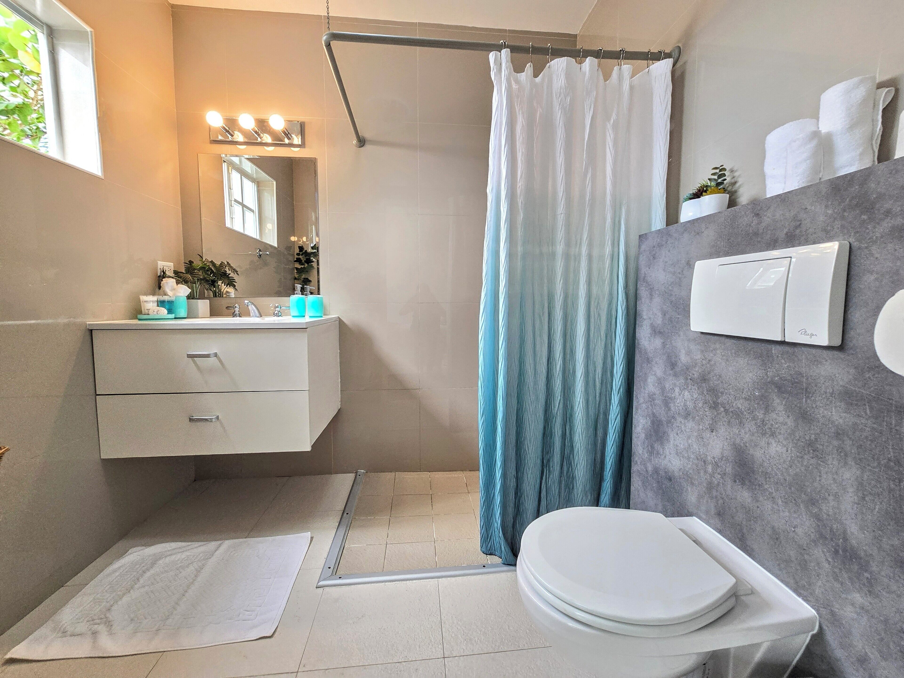 Un baño moderno con un tocador blanco, una cortina de ducha, un inodoro y un perchero para toallas.