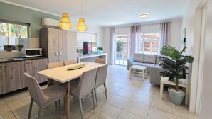 A modern kitchen with a dining area, a sofa, and a large window. - Bubali Villa & Apartments (Oranjestad)