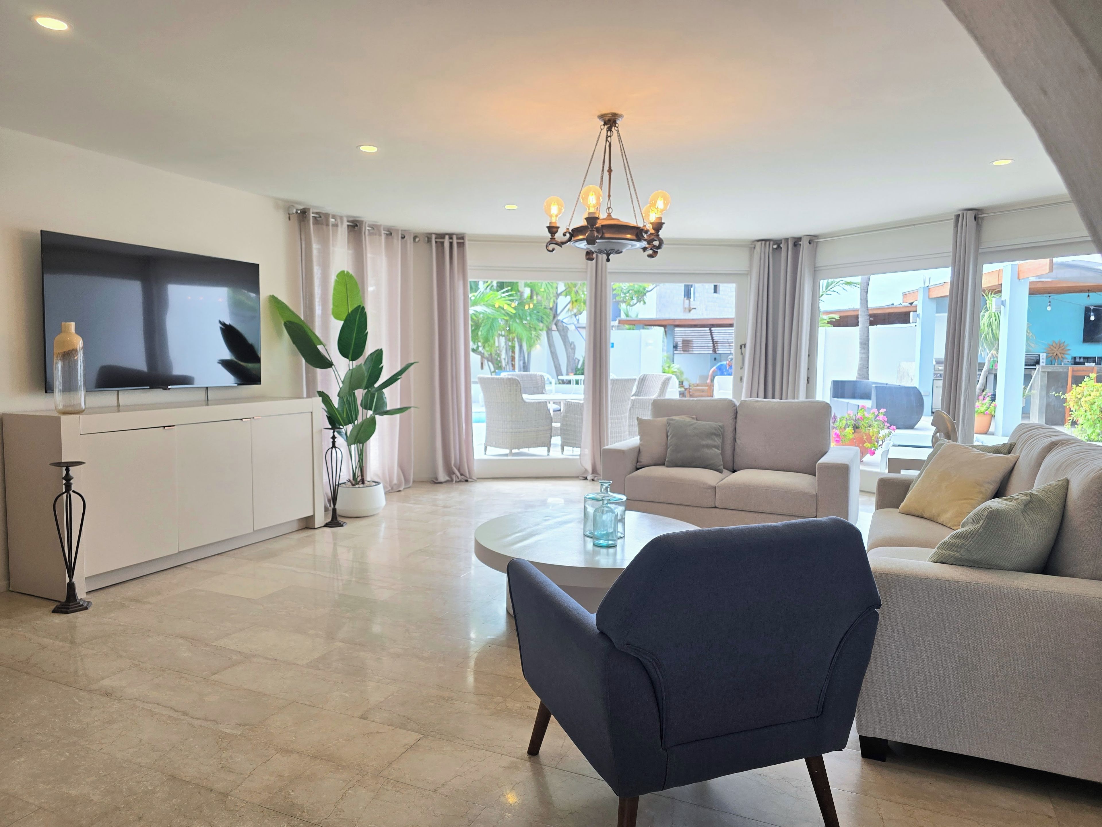 A modern living room with a flat-screen TV, a dining table, and a sofa.