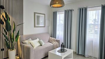 A modern living room with a sofa, a coffee table, a potted plant, a wall-mounted picture, and a ceiling light.