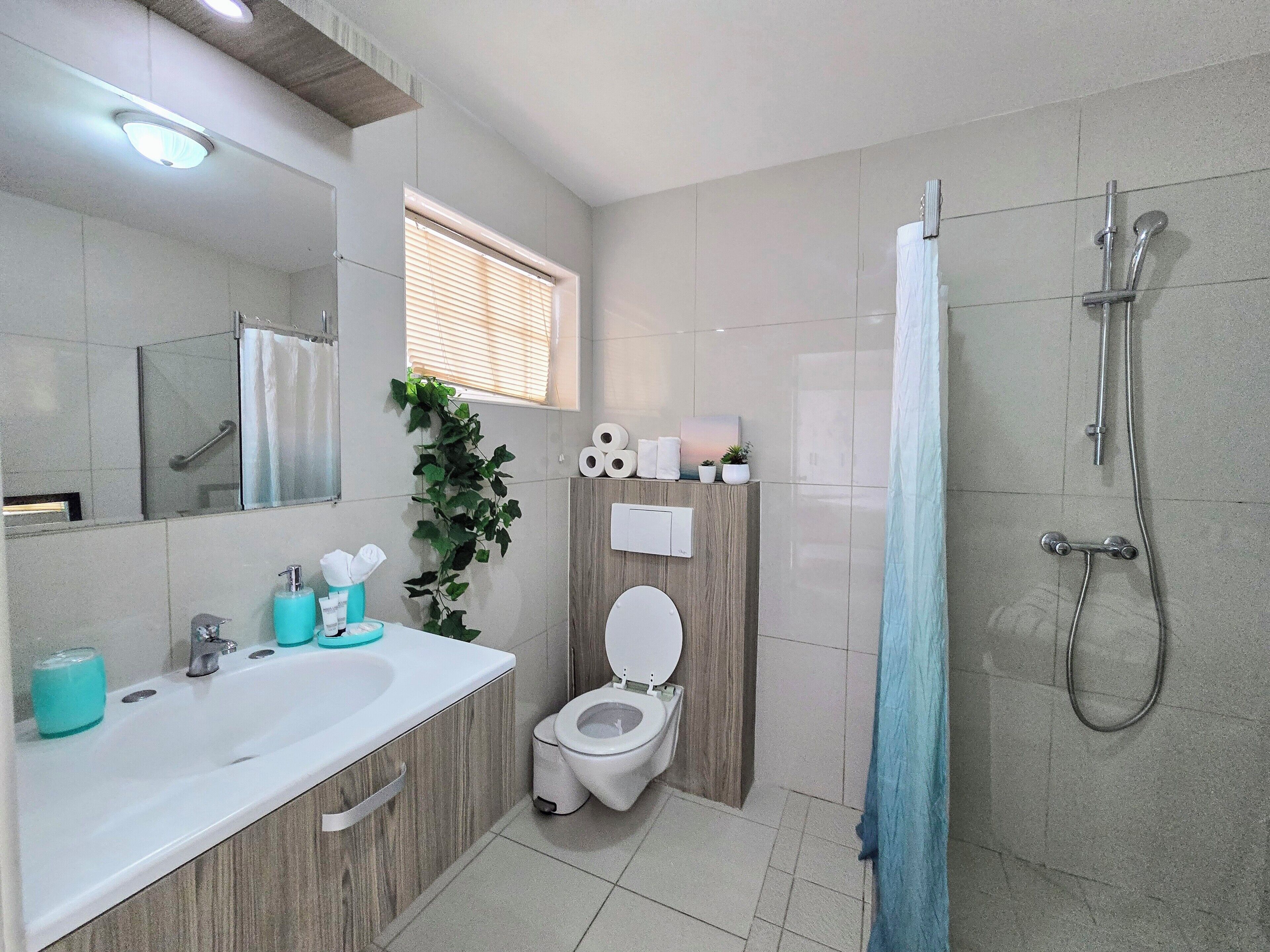 Un baño moderno con lavamanos, inodoro y ducha.