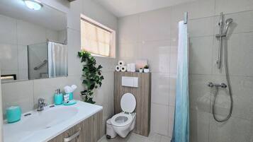 Un baño moderno con lavamanos, inodoro y ducha.