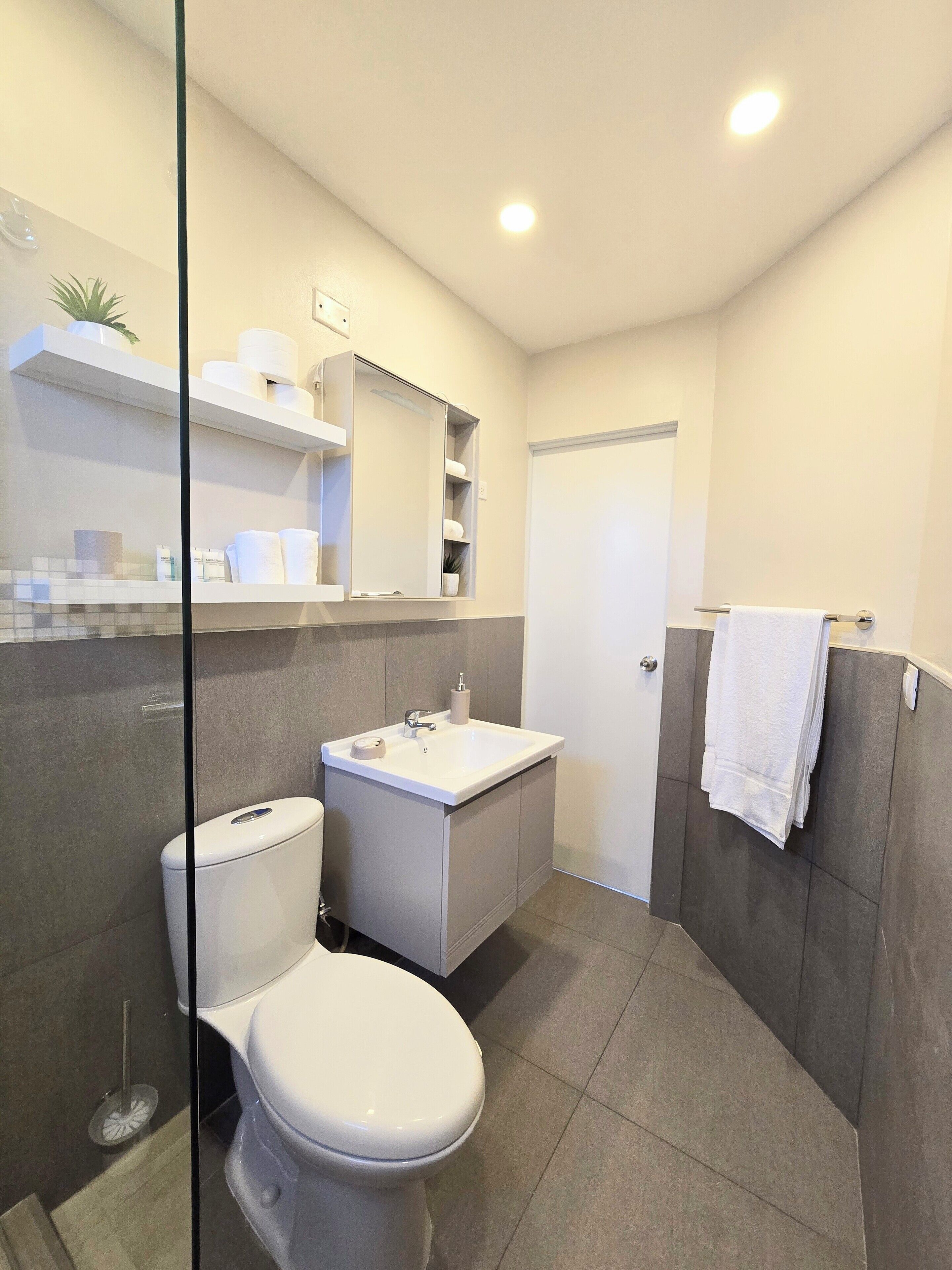 Ein modernes Badezimmer mit Toilette, Waschbecken und Spiegel.