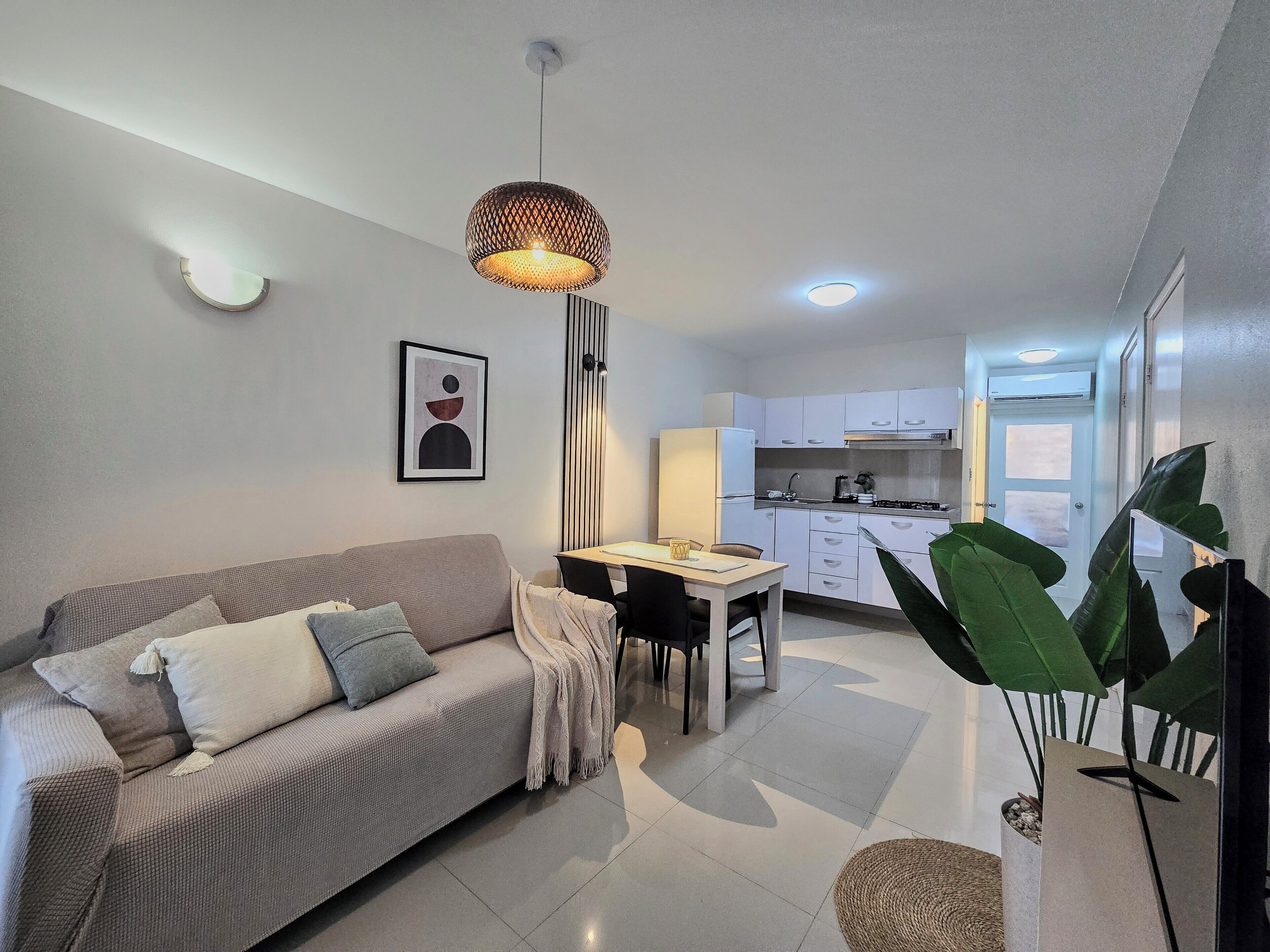 A modern living room with a sofa, a dining table, and a kitchen in the background.
