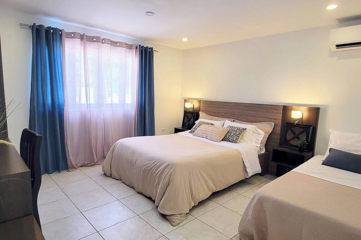 Habitación de hotel con cama, mesitas de noche y una planta en maceta.