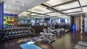 Een moderne sportschool met trainingsapparatuur, gewichtrekken en een spiegelwand.