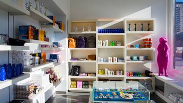 Un espacio comercial moderno con estantes llenos de diversos productos, una mesa de exhibición con artículos y una gran escultura rosa.