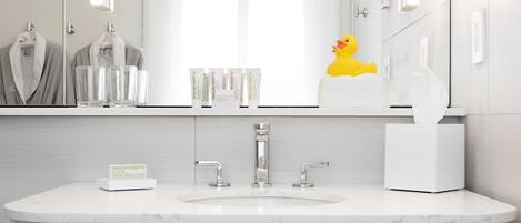 Un baño moderno con un lavamanos blanco, dos grifos y un espejo encima.