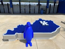 A blue sculpture of a bird on a blue carpet with the UK logo.