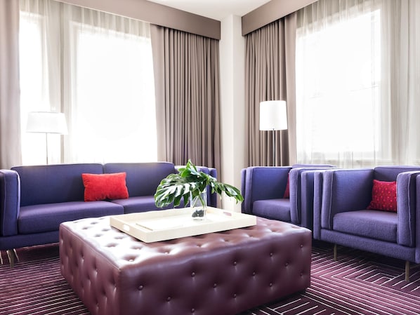 Habitación de hotel con dos sofás, una mesita de centro y una planta en maceta.