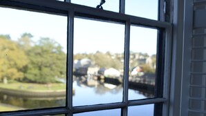 A window with a view of a calm body of water, a dock, and greenery. - Steam Packet Inn (Totnes)